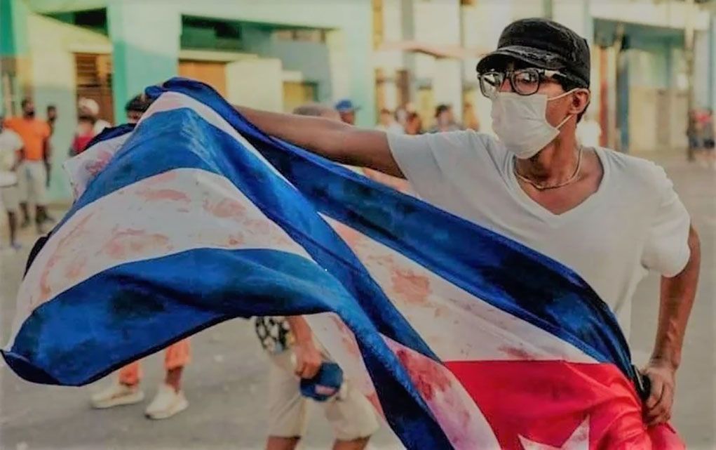 Demonstrator raises a bloody flag on July 11 during the popular revolt in Cuba.